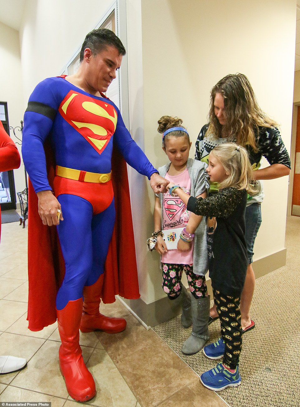 Zowie Sanders, gives a fist bump to John Suber, left, of Greenville, dressed as Superman, with her sister Lindsey Sanders, center, and their mother Brooke Starks, right, of Townville, during a wake service for Jacob Hall