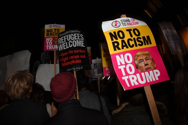 Demonstrators hold placards that read "No to racism, no to Trump" during a protest outside the US Embassy in London