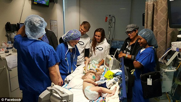 Their parents Nicole and Christian (pictured in white) stand in the ward with the surgeons as the boys get ready for their 20-hour surgery on October 13 in Montefiore Hospital