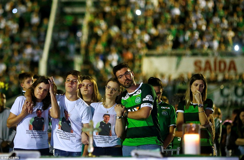 Huddled together: Relatives pay tribute to Chapecoense's players at the Arena Conda stadium in Chapeco, Brazil