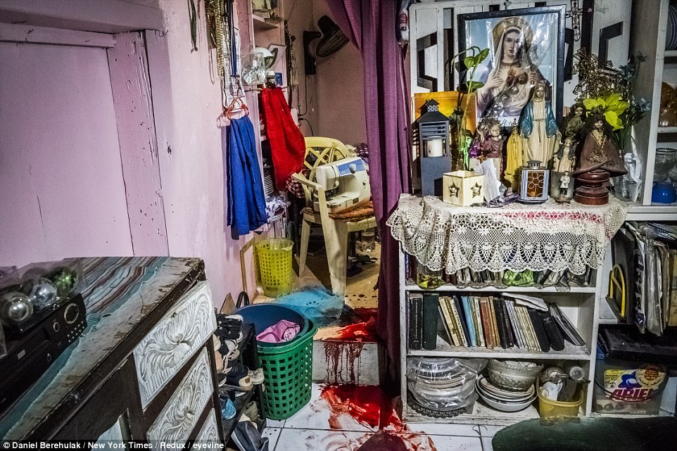 The blood of Florjohn Cruz, 34, stains the floor in his family's living room, next to an altar displaying images and statues of the Virgin Mary, among other items, in Manila, Philippines
