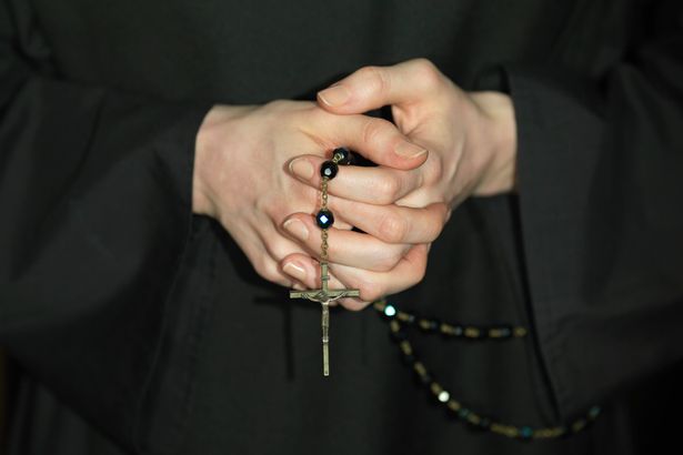 A nun's hands holding a rosary