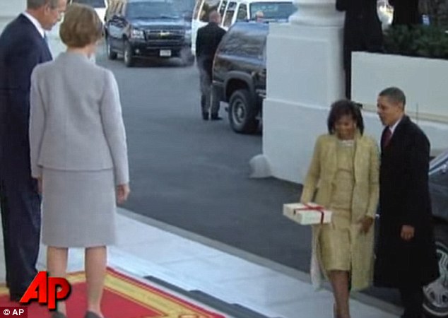Michelle, holding a gift for Laura Bush, was escorted by Barack up the White House stairs