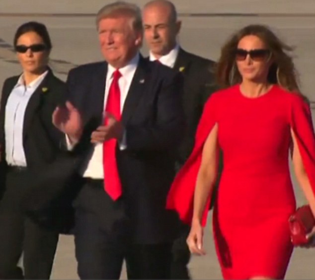 The presidential couple were initially seen holding hands, but Trump abruptly let go to clap along with the well-wishers who had come to greet him (pictured)
