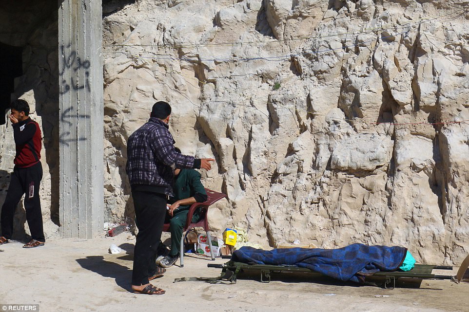 People stand near a dead body, after what rescue workers described as a suspected gas attack in the town of Khan Sheikhoun in rebel-held Idlib, Syria