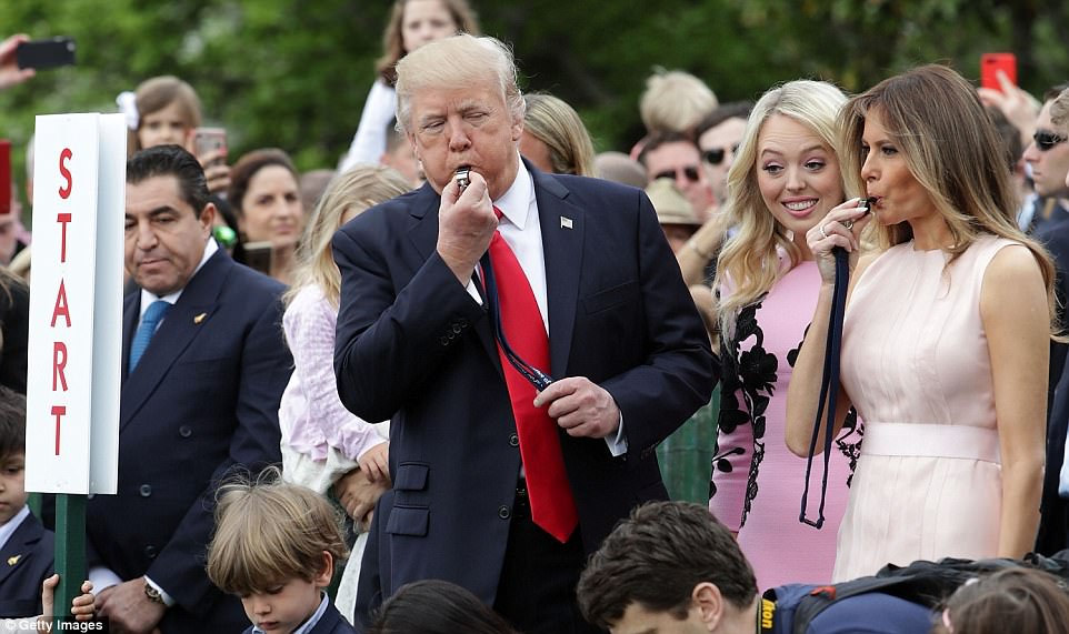 Daughter Tiffany Trump is seen peeking through her father President Trump and stepmother Melania Trump as kids beginning rolling their eggs through the White House lawn 