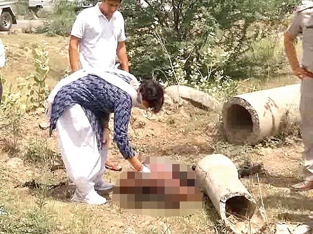 Police found the 23-year-old's mutilated body being torn apart by dogs at an industrial site in Rohtak district (pictured - an official exams the victim's body)
