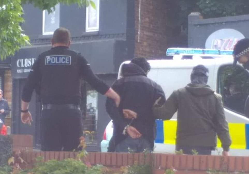 Footage shows officers leading the handcuffed 23-year-old to a police van outside a Morrisons supermarket in Chorlton-Cum-Hardy, south Manchester at about 10.30am this morning