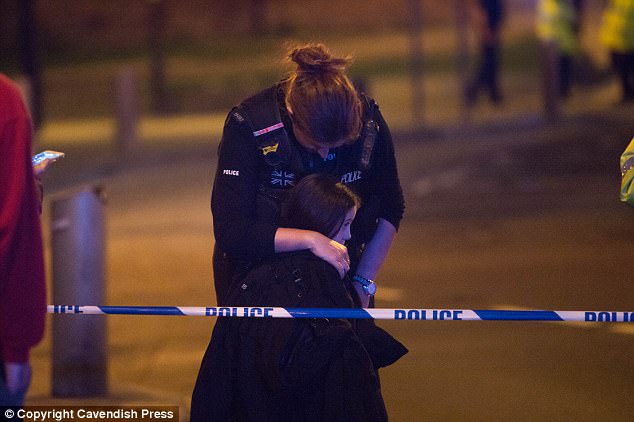 A female police officer comforts a devastated young girl outside the stadium last night 