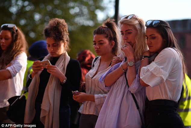 People pause in front of candles set up in front of floral tributes in Albert Square in Manchester, northwest England